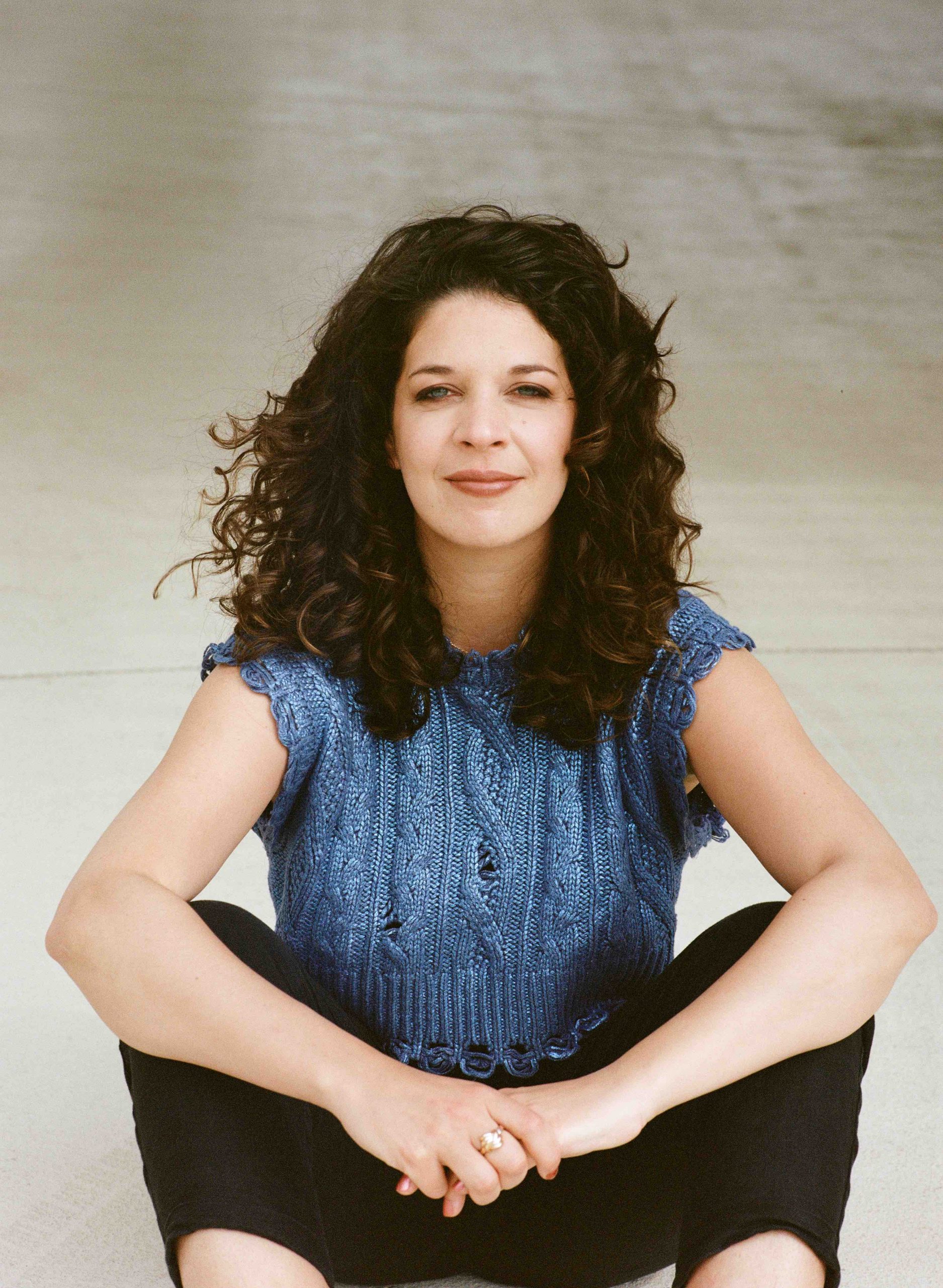 Portrait of Ines Khannoussi, a filmmaker, in Vienna on a sunny day, with her looking directly into the camera.